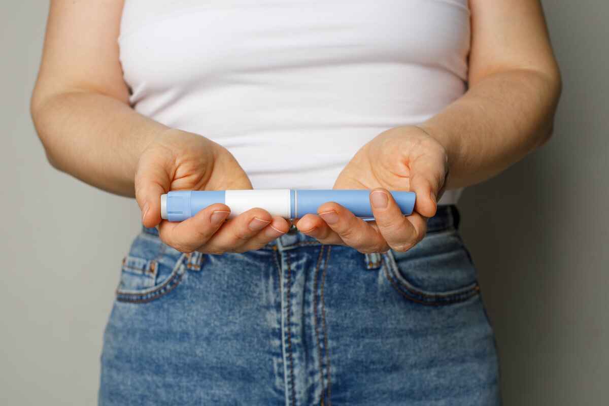 Woman holding GLP-1 injector pen like Ozempic